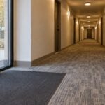Clean carpeted apartment building hallway with a walk-off mat at the entrance in autumn